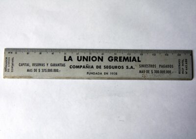 Regla metálica con Calendario Año 1964 de La Unión Gremial Compañía de Seguros Sociedad Anónima.